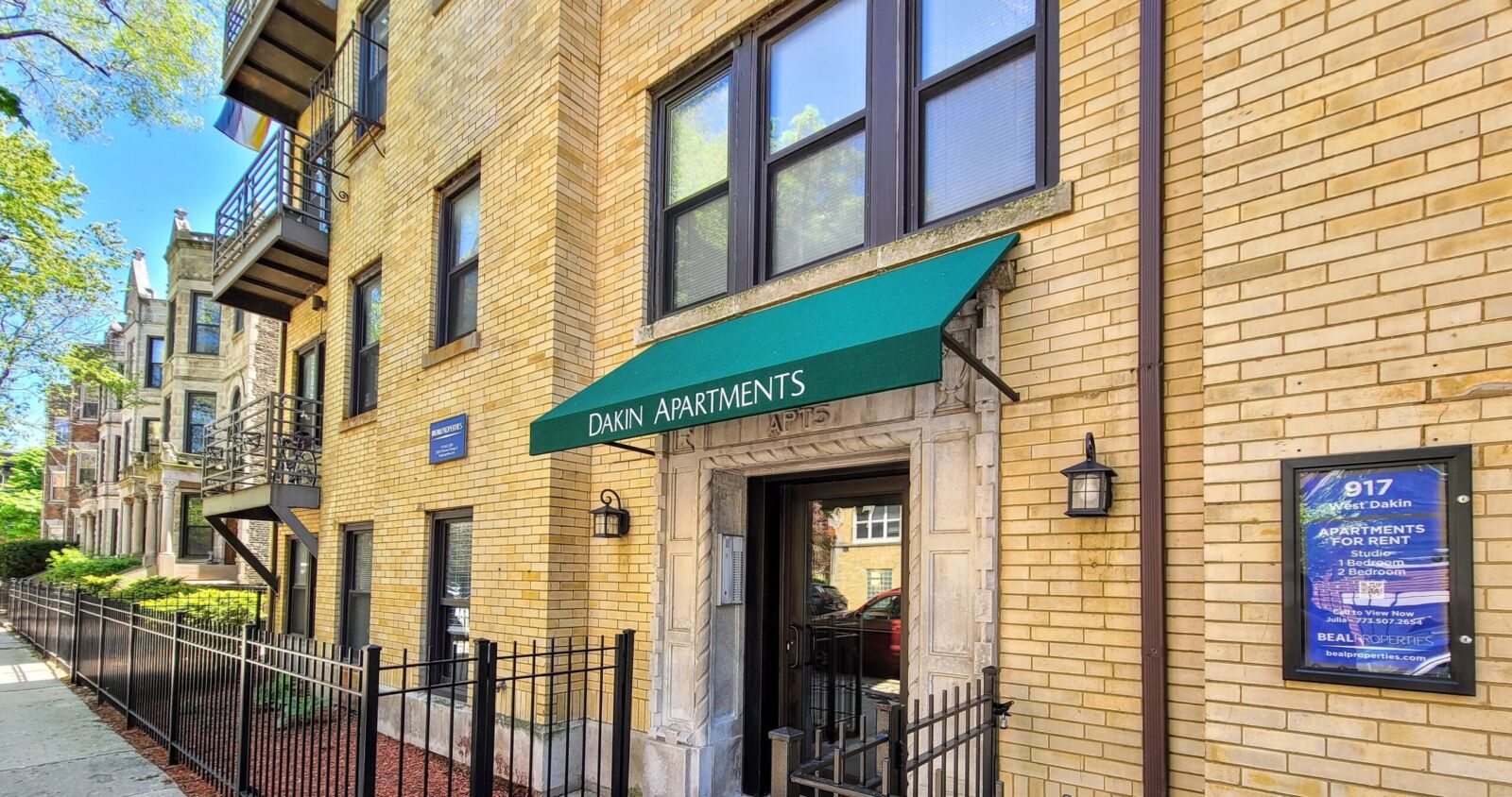Close-up view of the front entrance to 917 West Dakin, a yellow brick apartment building in Chica...