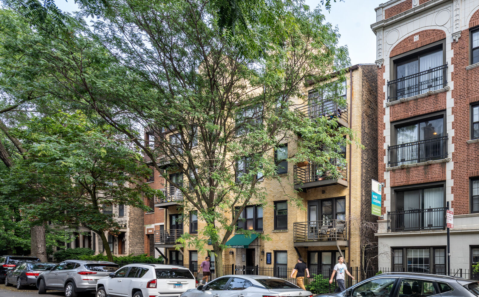 Four-story tan brick apartment building with balconies and green awning at 917 W Dakin Street in ...