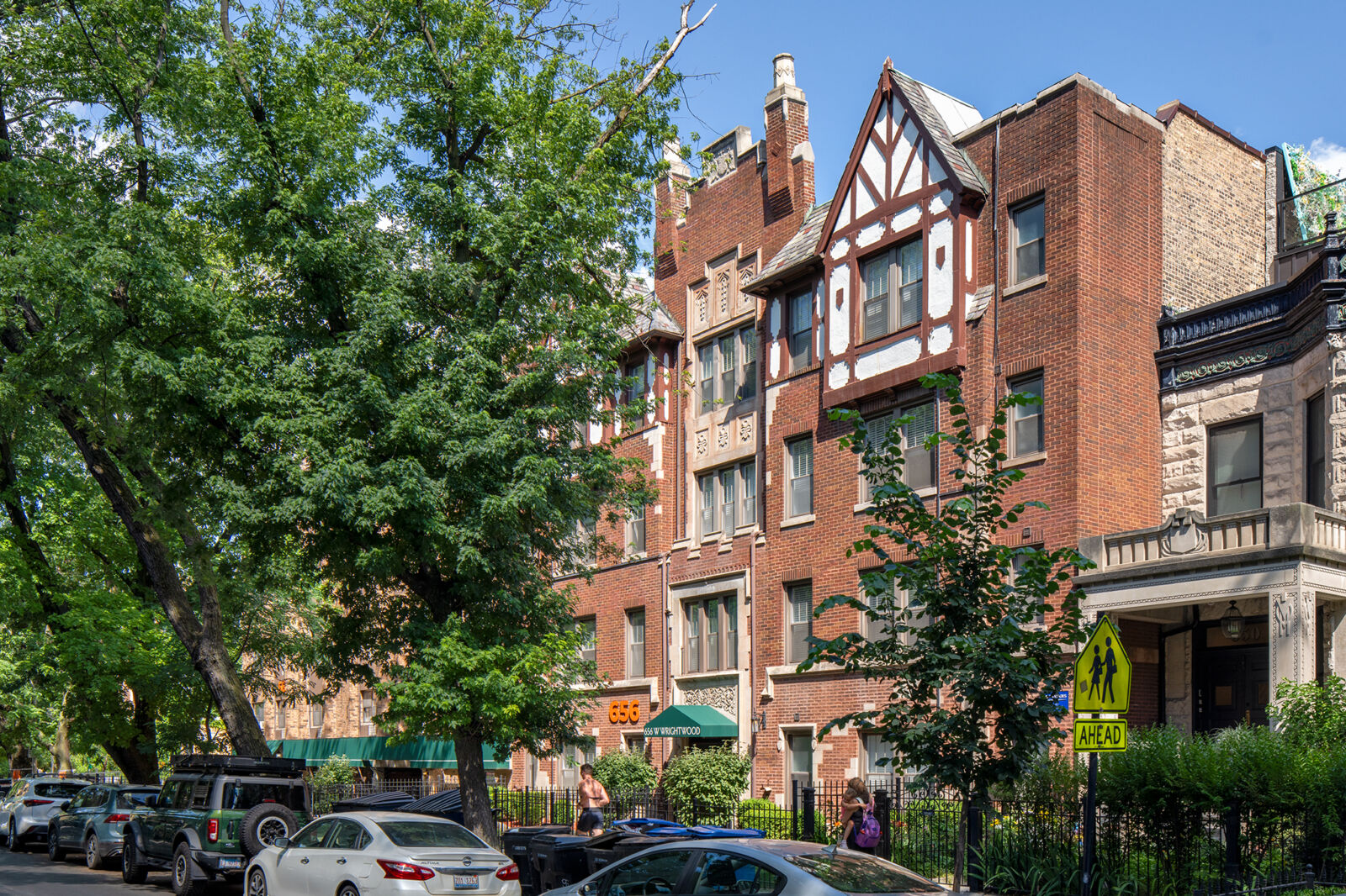 Street-level view of 656 W Wrightwood, a red brick Tudor-style apartment building with decorative...