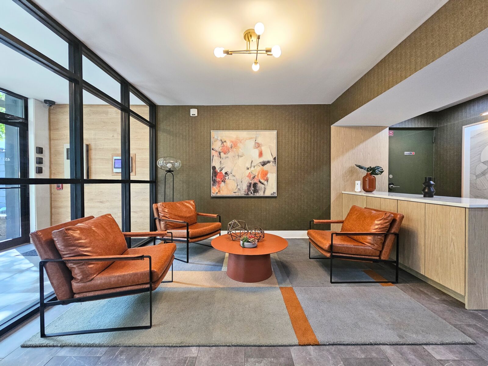 Lobby seating area with four leather armchairs, geometric decor, and textured olive-green accent ...