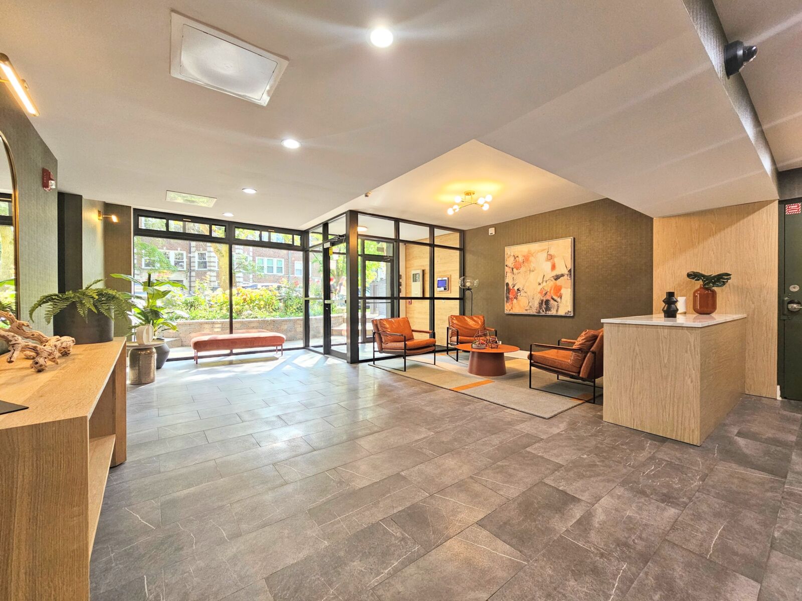 Lobby with modern lounge seating, light wood reception desk, and natural light from large glass e...