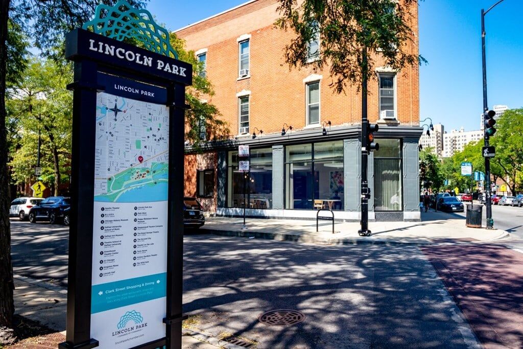 Lincoln Park street corner with neighborhood map kiosk and historic red-brick mixed-use building ...