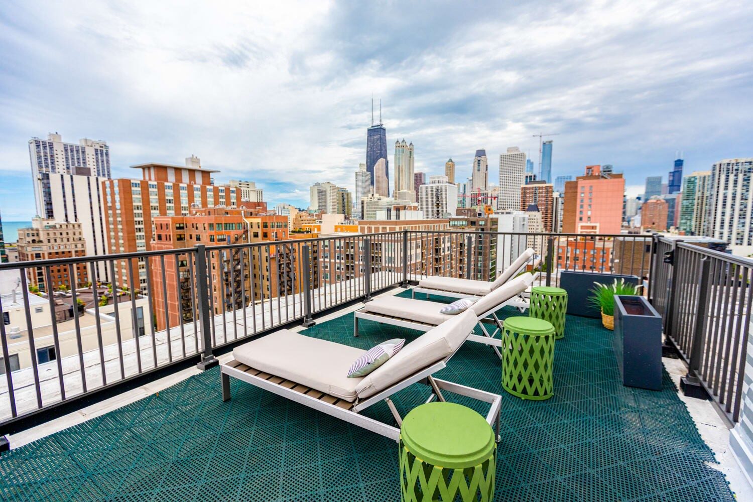 Rooftop terrace with lounge chairs, skyline views, and green accent tables facing downtown Chicago.