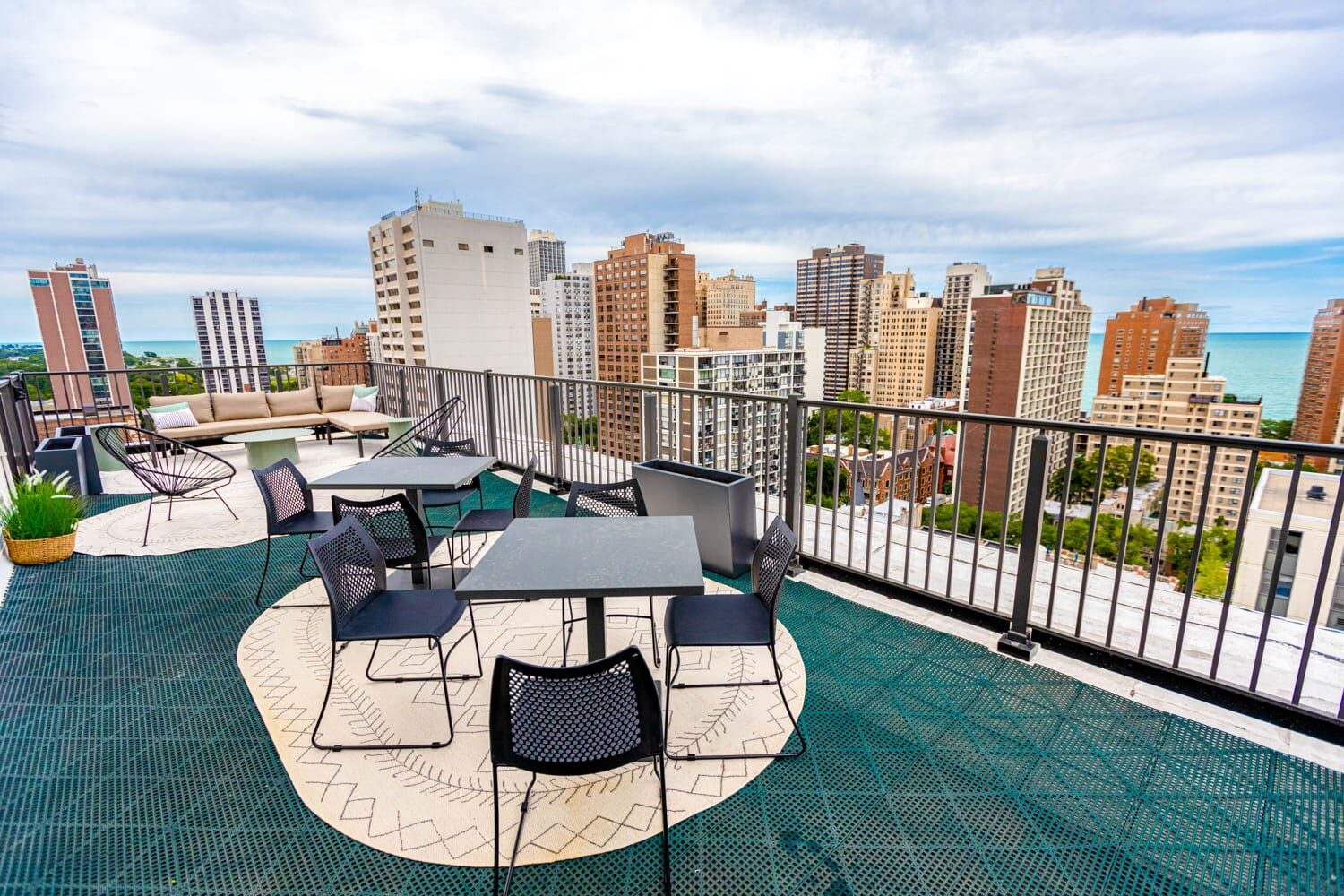 Rooftop lounge with dining tables, outdoor seating, and lake and skyline views.