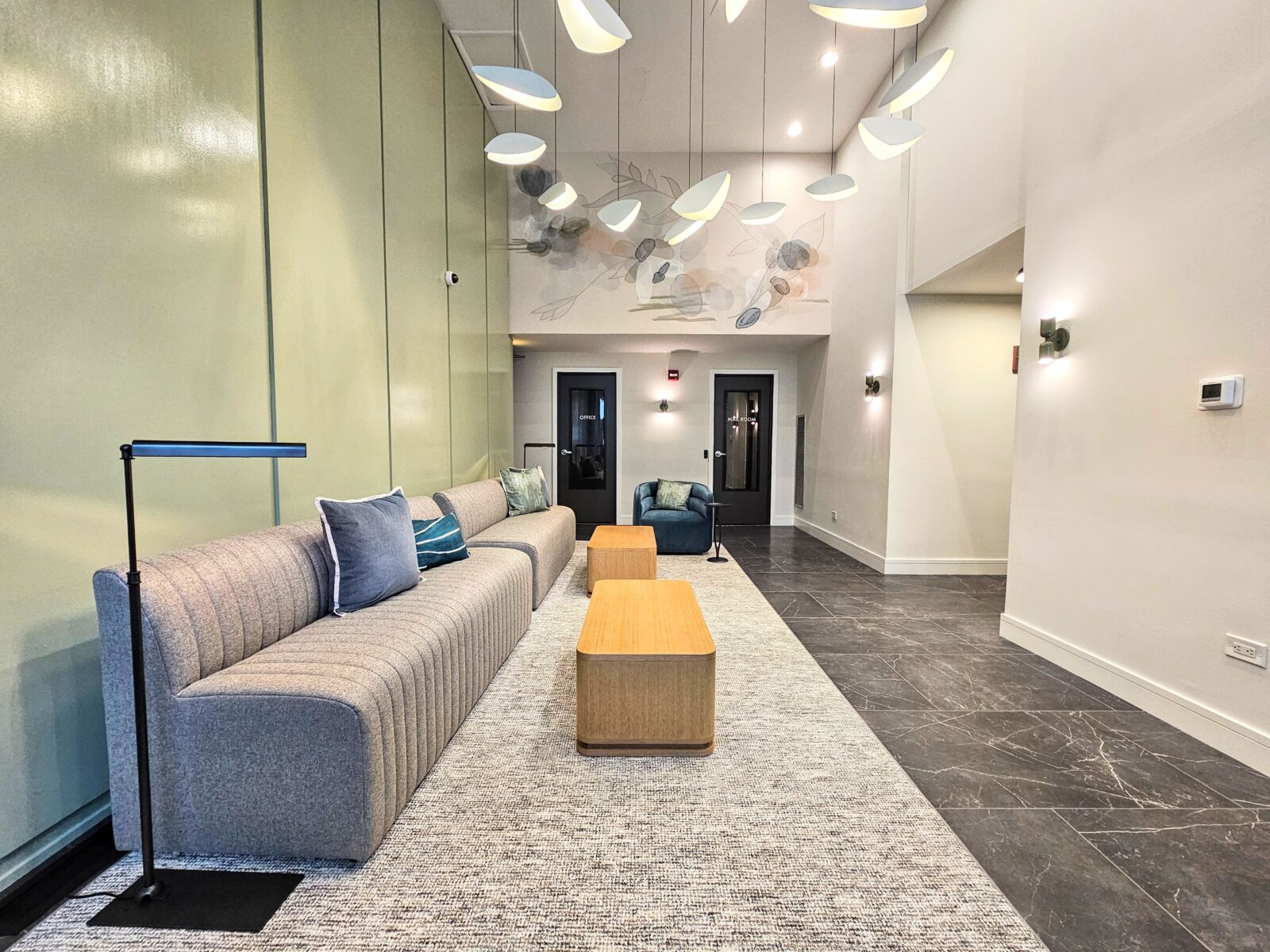 Modern lobby with tufted sofa, pendant lighting, and dark tile flooring.