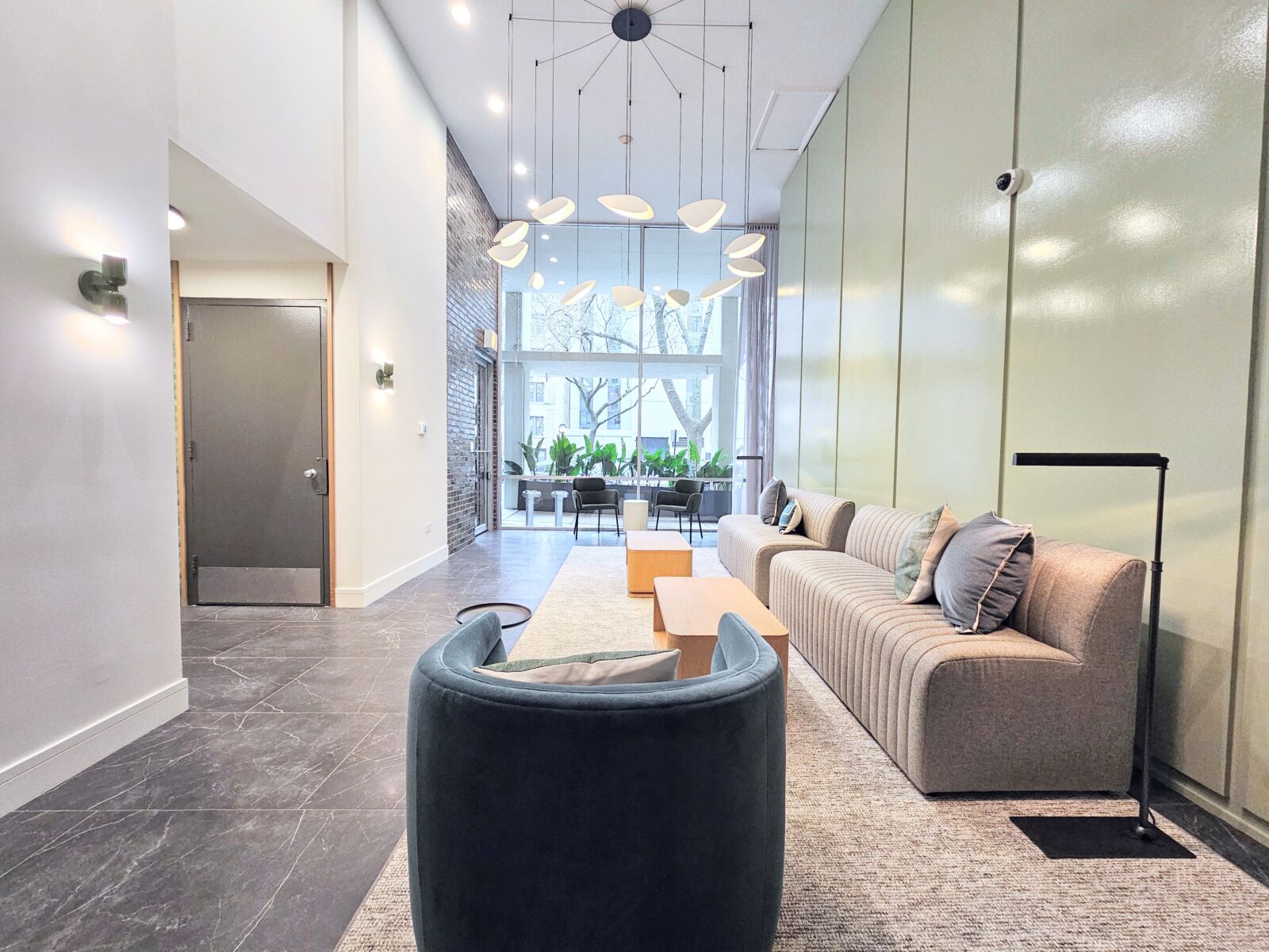 Lobby with high ceilings, modern light fixture, velvet accent chairs, and floor-to-ceiling windows.