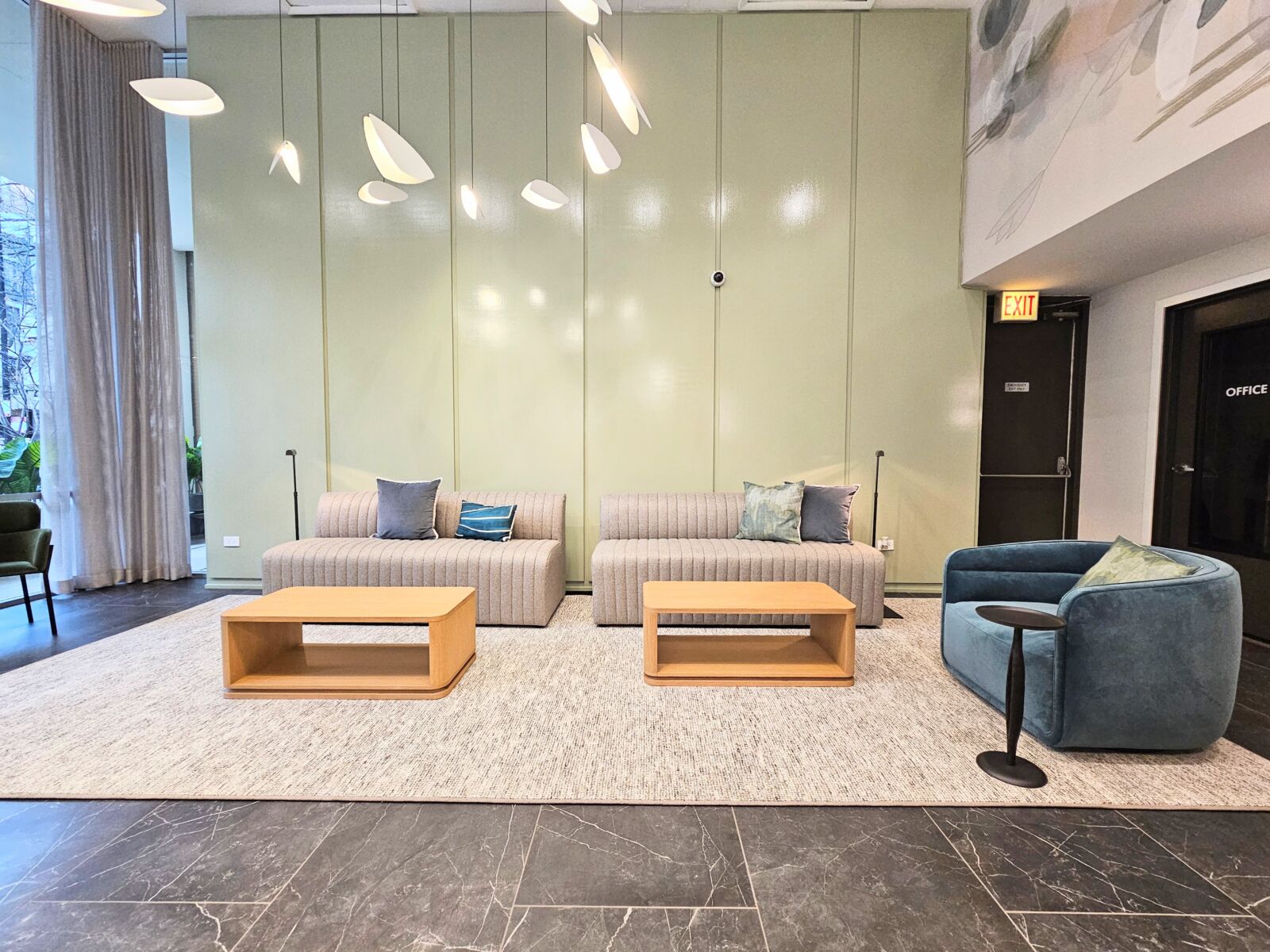 Lobby seating area with twin tufted sofas, wood coffee tables, and artistic pendant lighting over...