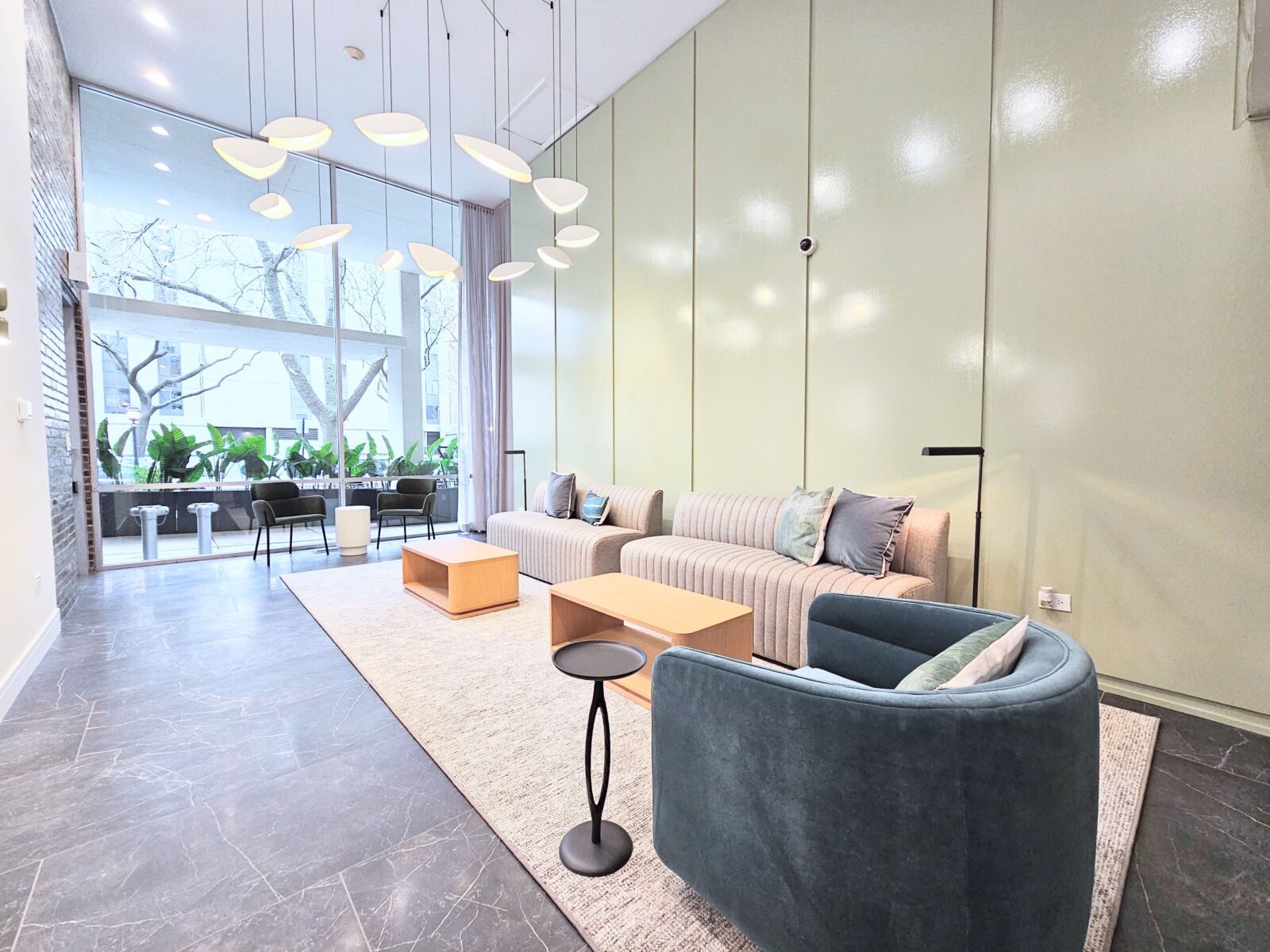 Lobby with floor-to-ceiling windows, sculptural lighting, and contemporary seating in soft neutra...