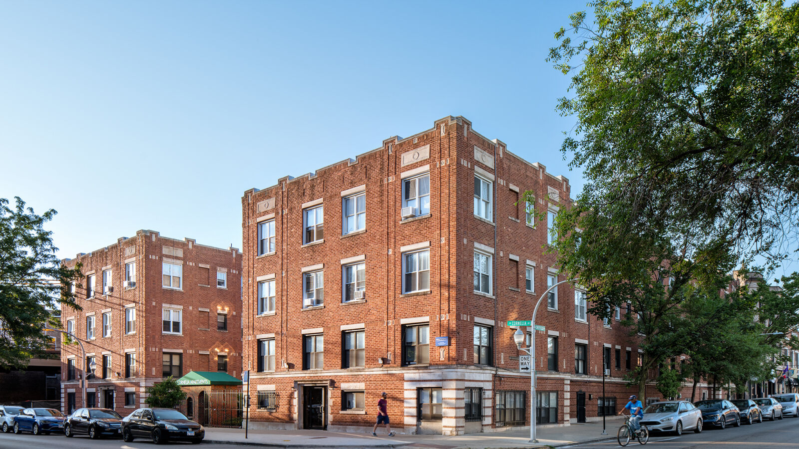 Red brick courtyard apartment building with decorative stone accents and green awning at 947–957 ...