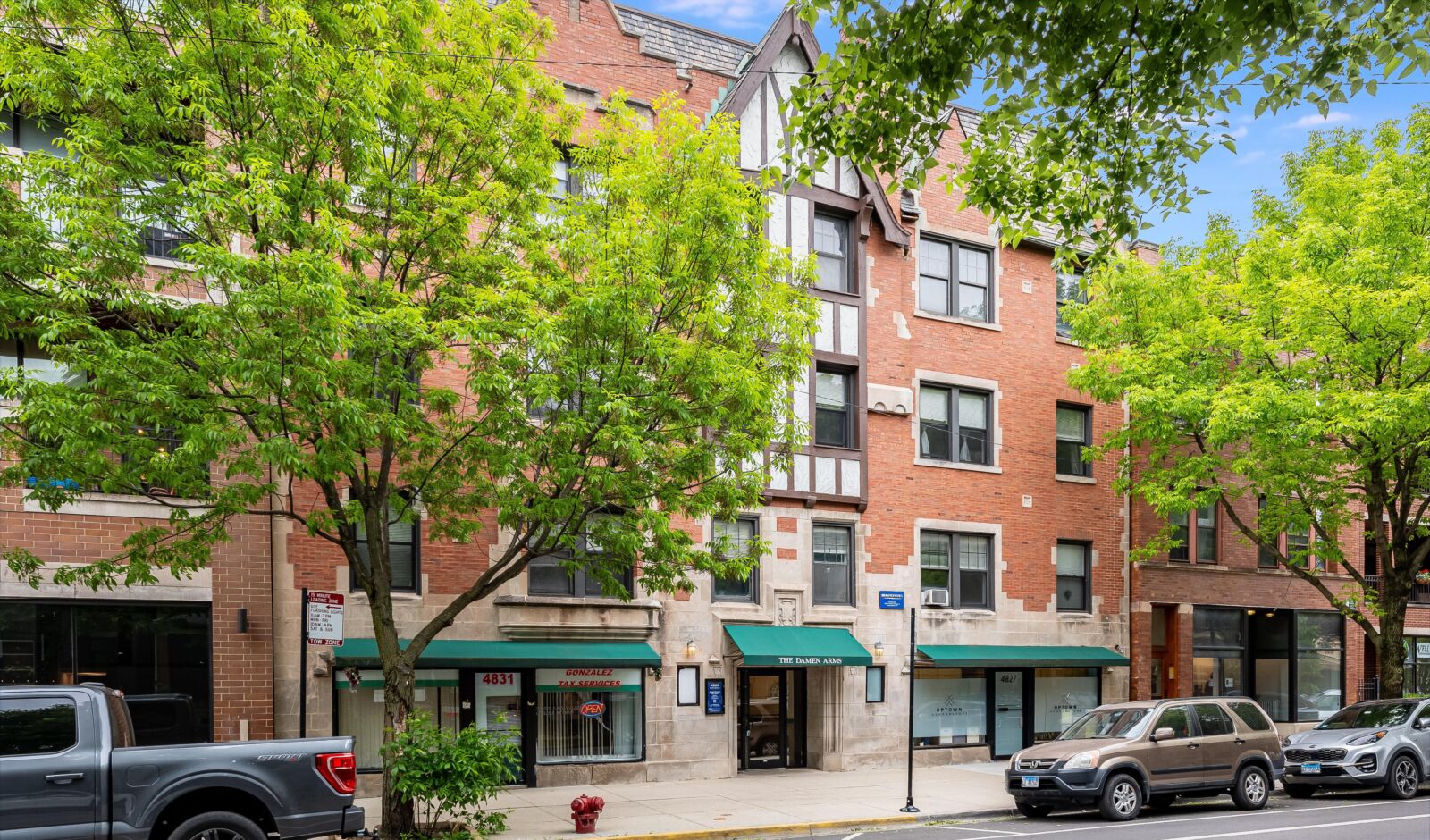 Tudor-style red brick apartment building with green awnings and decorative half-timber details at...