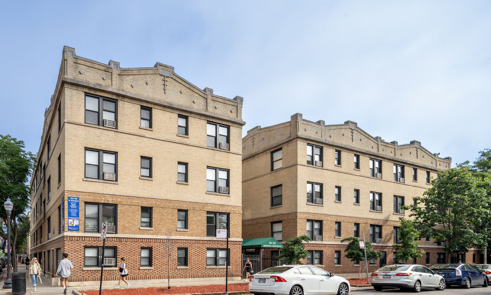 Traditional tan and brown brick courtyard apartment building with decorative rooflines at 705–715...