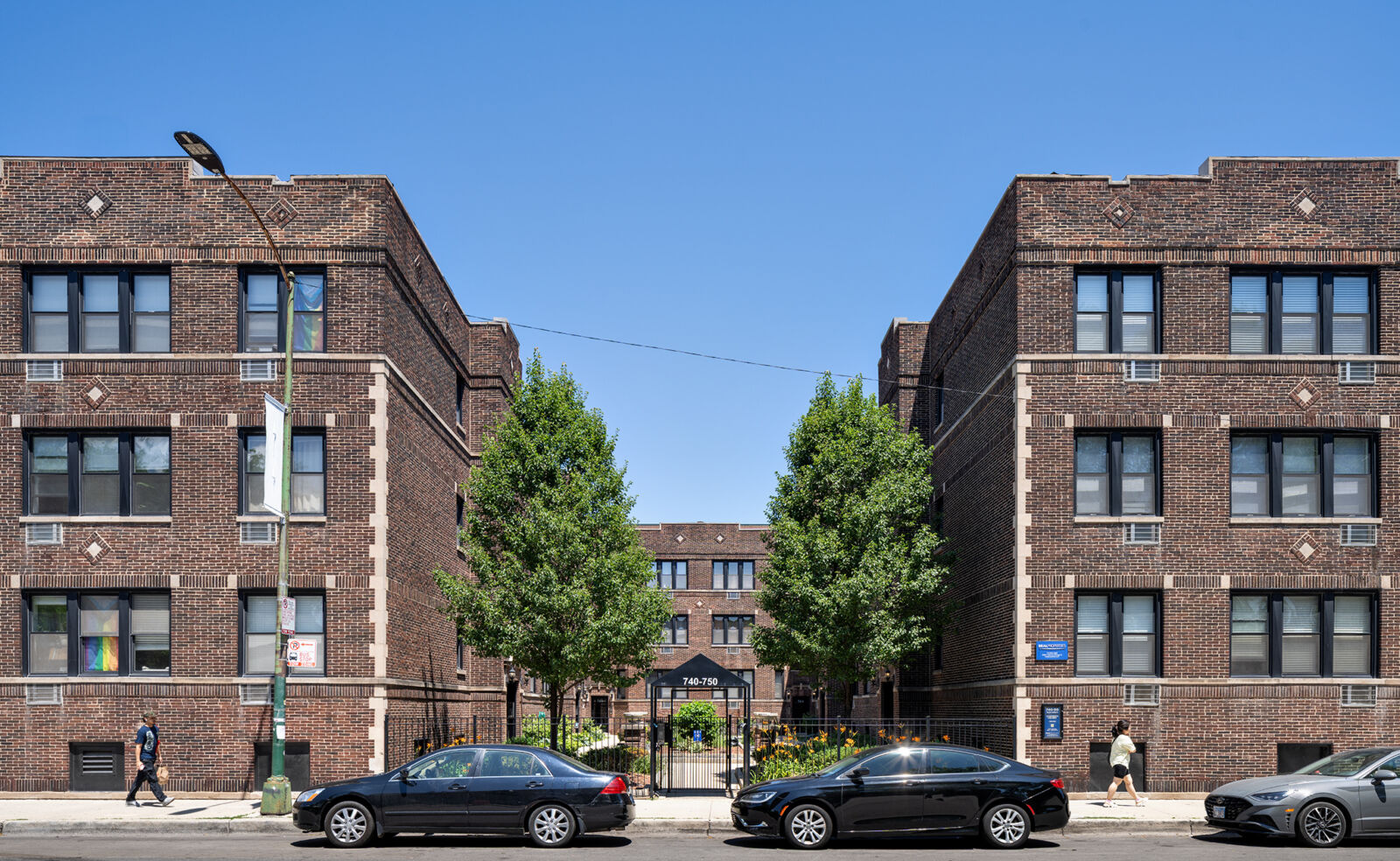 Classic red brick courtyard apartment buildings with decorative stone insets at 740–750 W Addison...