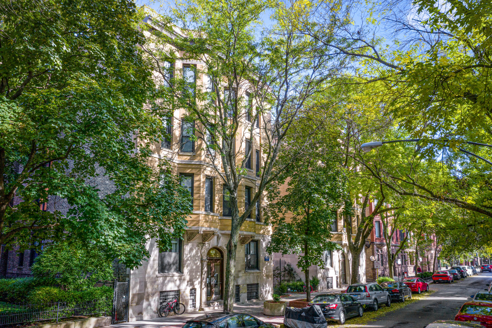 Tree-lined residential street with a beige stone apartment building at 428 W Belden Avenue in Chi...