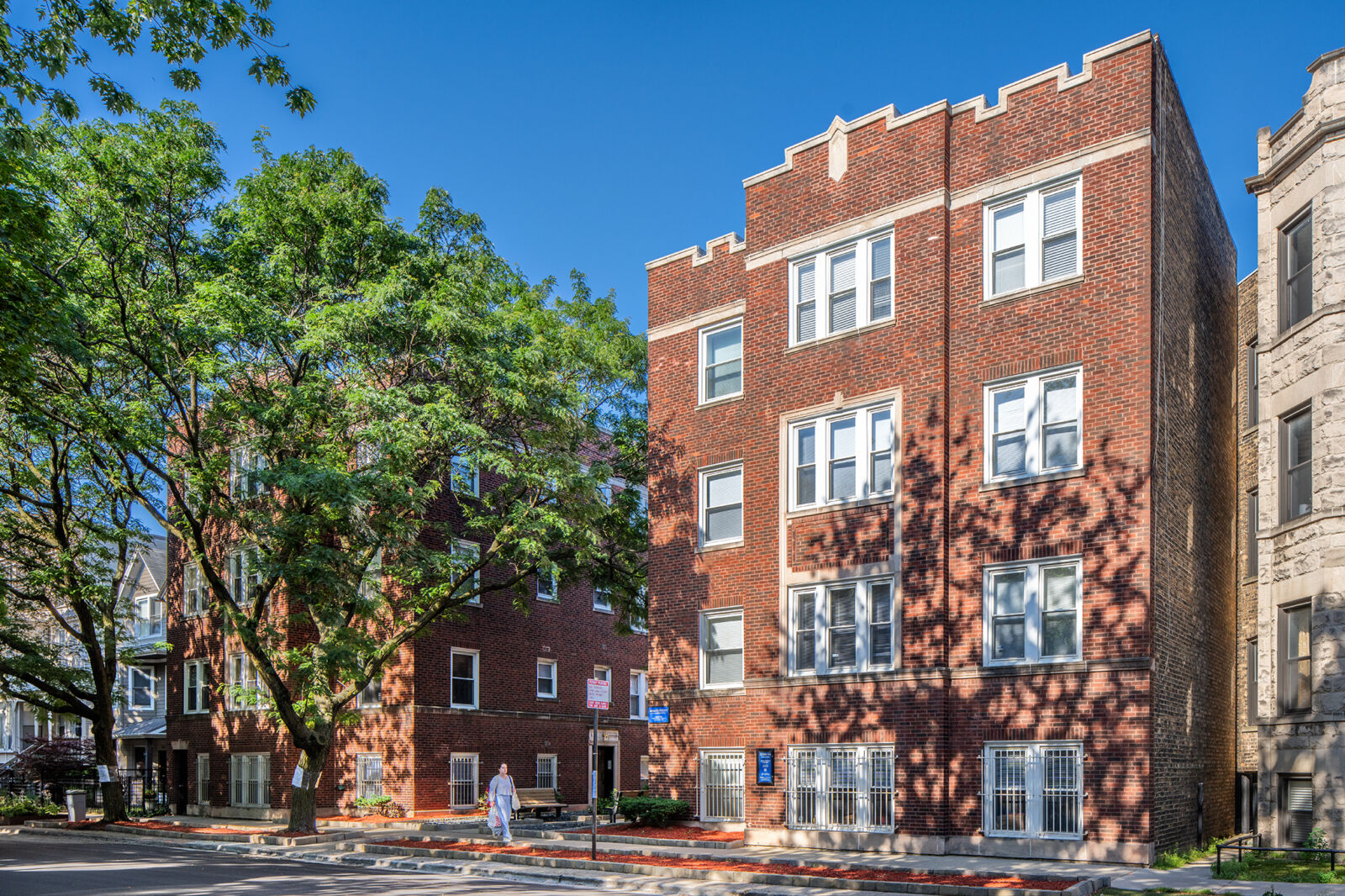 Red brick courtyard apartment building with white stone trim and castellated rooflines at 3244–32...