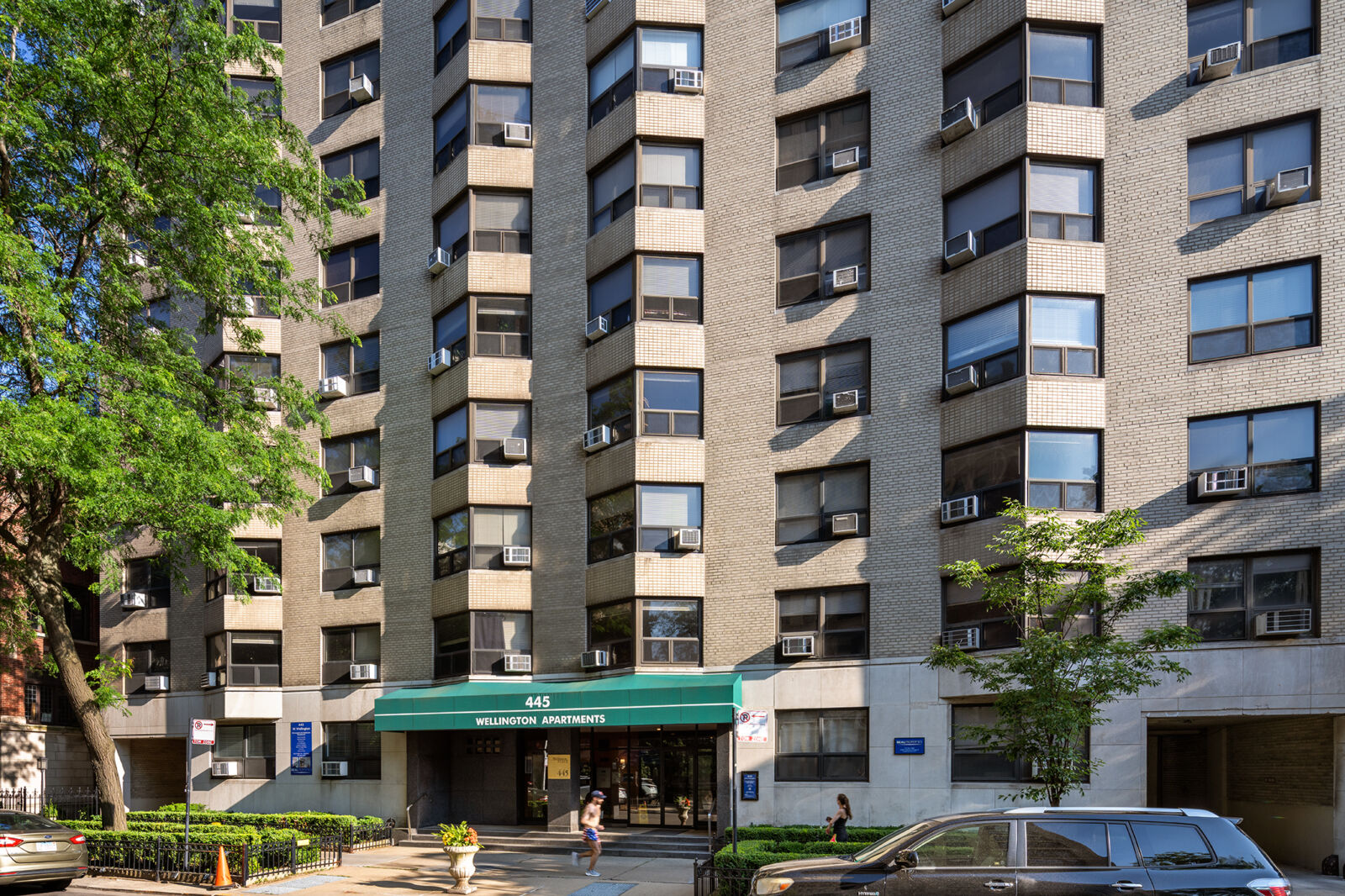 Street-level view of the front entrance to 445 W Wellington, showing green awning labeled “Wellin...