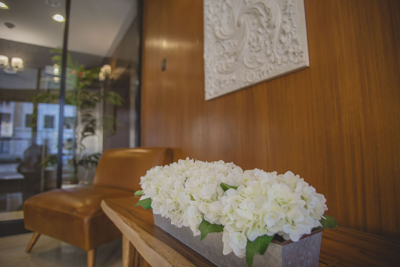 Lobby detail with leather chair, wood paneling, and fresh white hydrangeas on a rustic table.