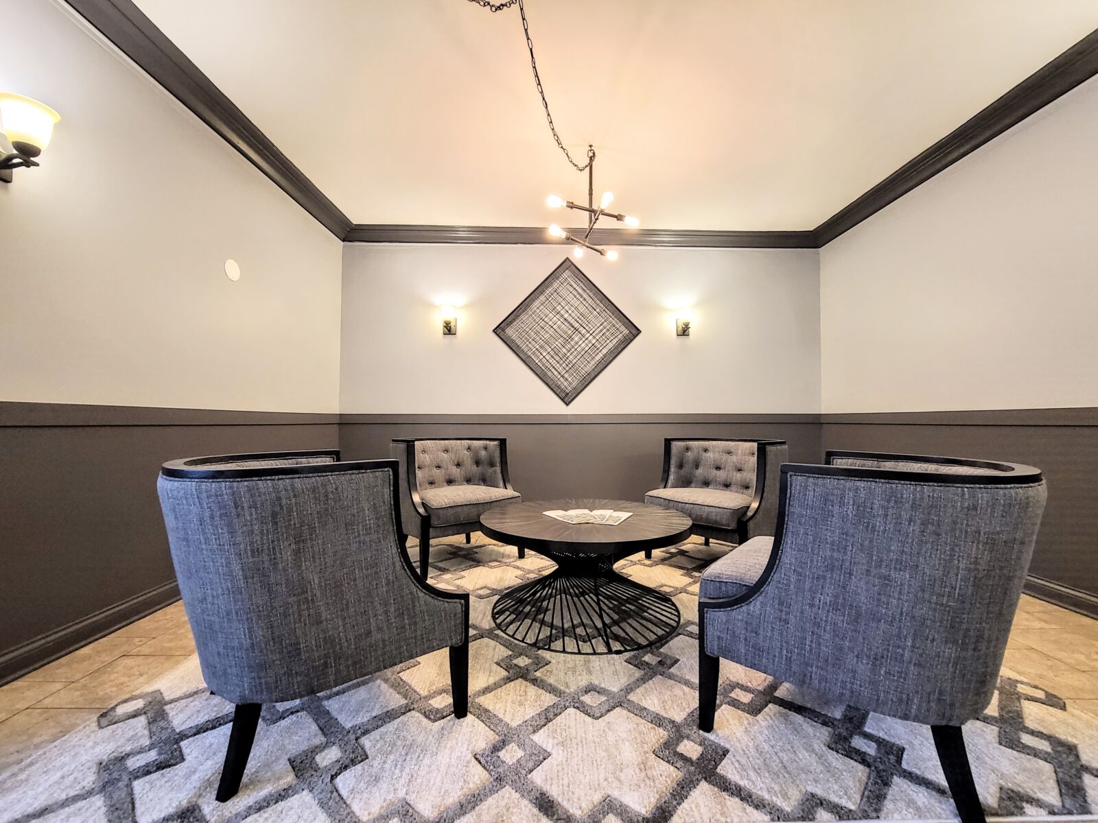 The main lobby of 837 West Wolfram with stylish gray tufted chairs, a fireplace with a mirror abo...