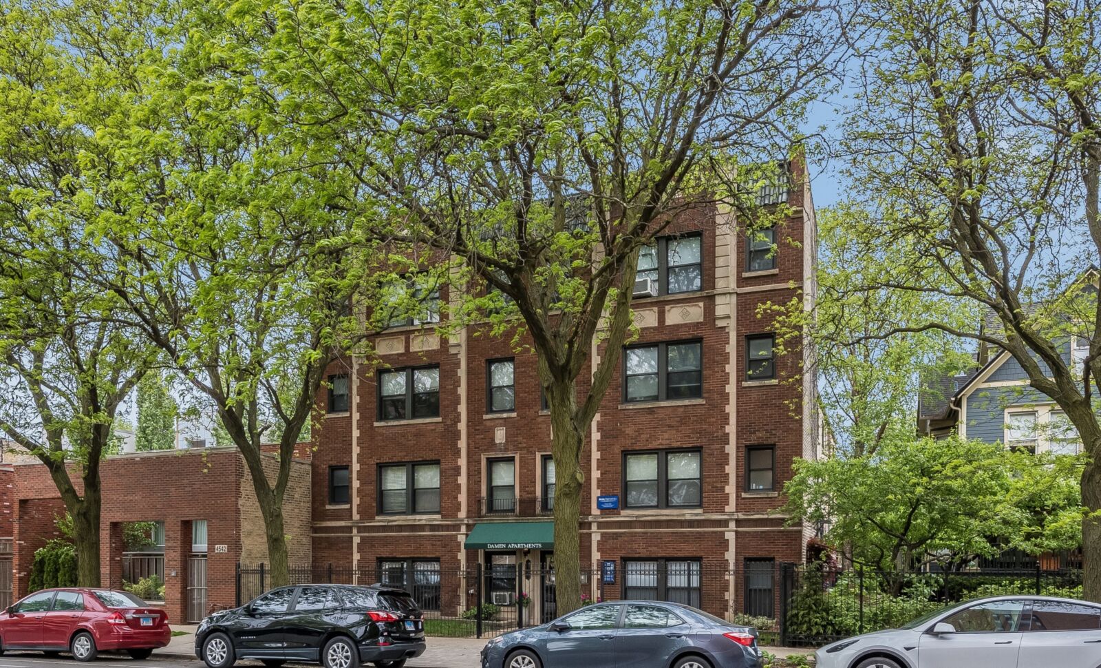 Four-story red brick apartment building with decorative stone accents and green awning at 4546 N ...