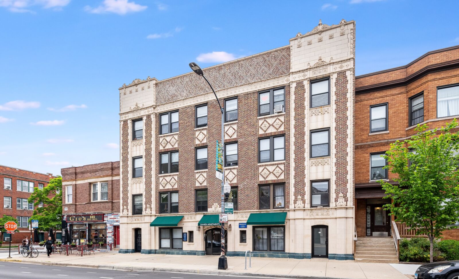Four-story brick apartment building with ornate terra cotta detailing and green awnings at 4851 N...