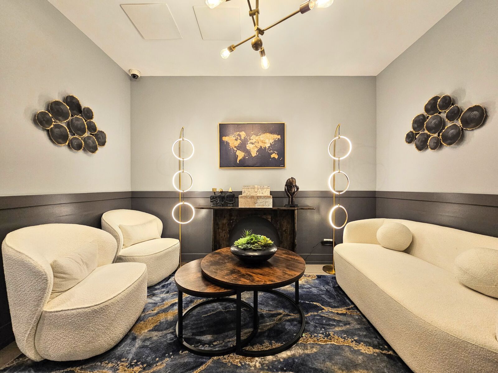 Lobby lounge with boucle chairs, round wood coffee table, and sculptural lighting against dark wa...