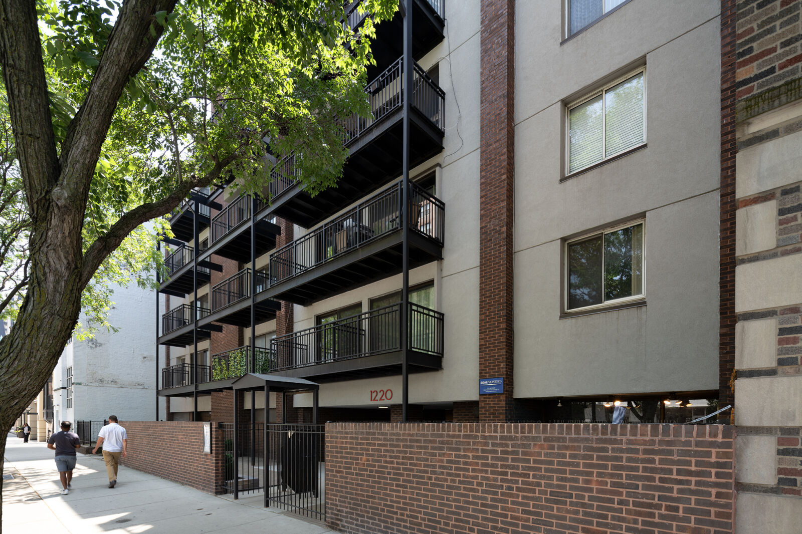 Angled side view of 1220 North LaSalle in Chicago, showing multiple stacked balconies, brick-and-...